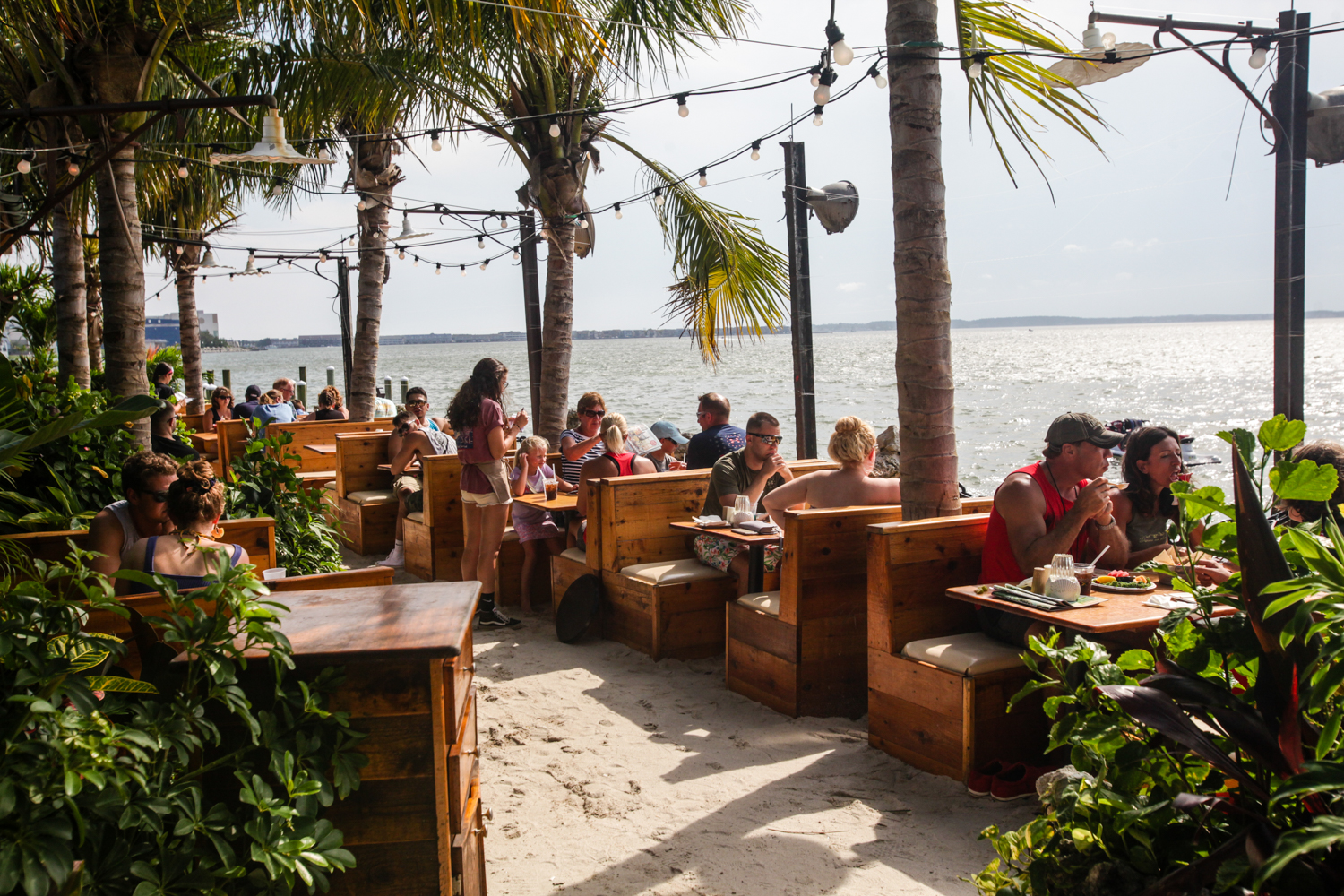 a group of people sitting at tables on the beach
