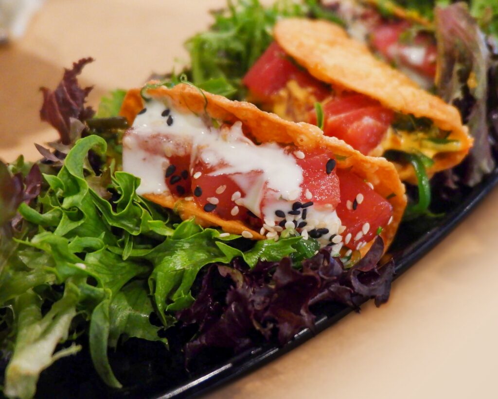 a black plate topped with a salad covered in toppings