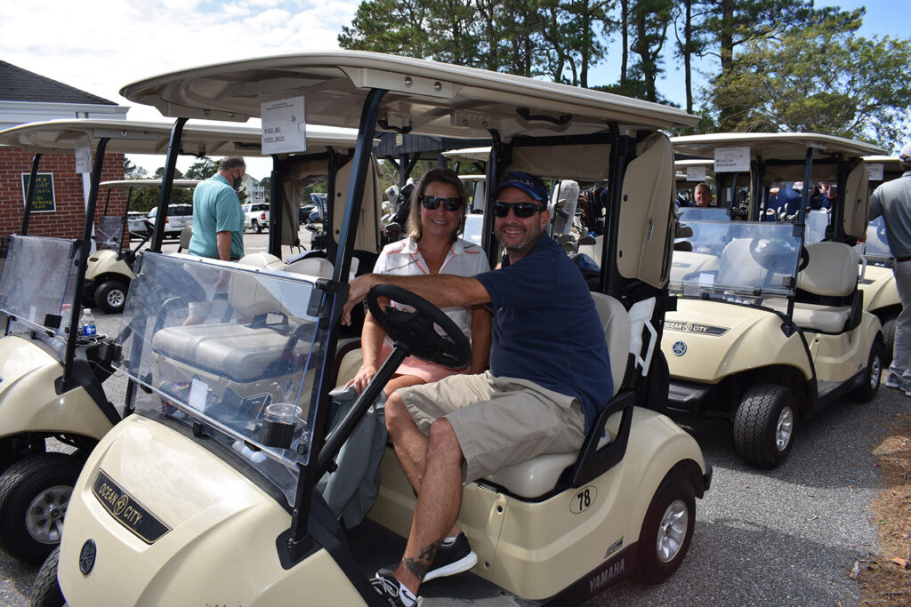 a couple of men riding on the back of a golf cart