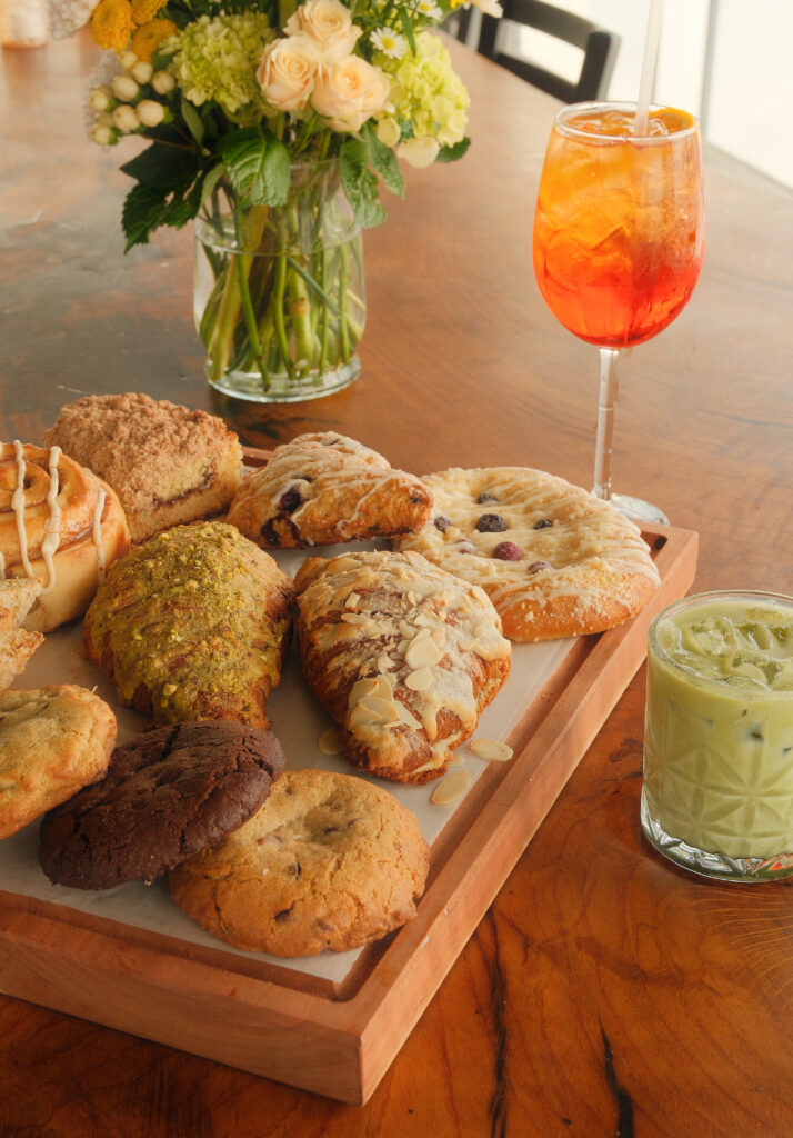 a wooden table topped with lots of cookies and pastries