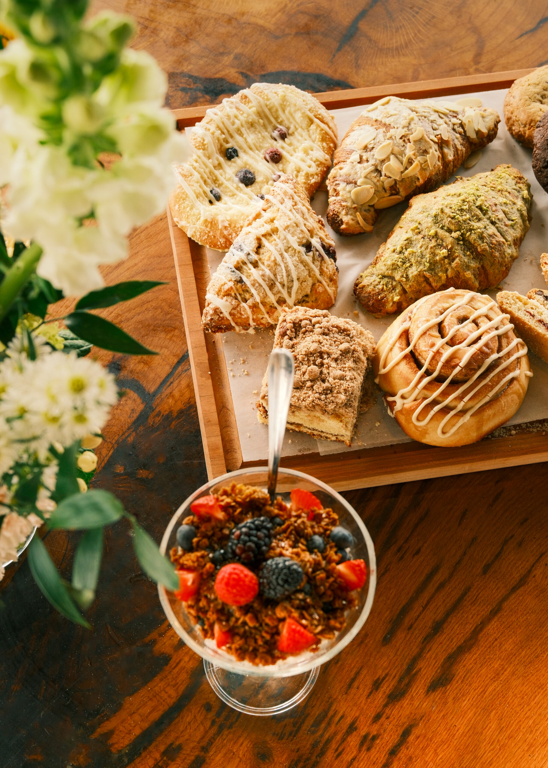 a wooden tray topped with pastries and a bowl of fruit