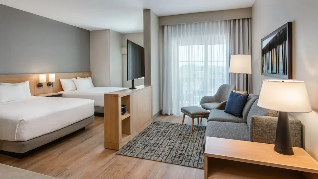 Hyatt Place Ocean City studio suite living area with sleeper sofa, TV, and large window .